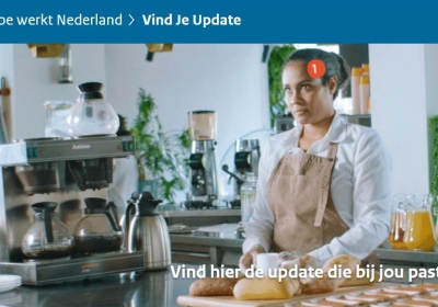 Vrouw werkt als barista en houdt een kopje koffie in haar hand. Tekst 'vind de update die bij jou past'